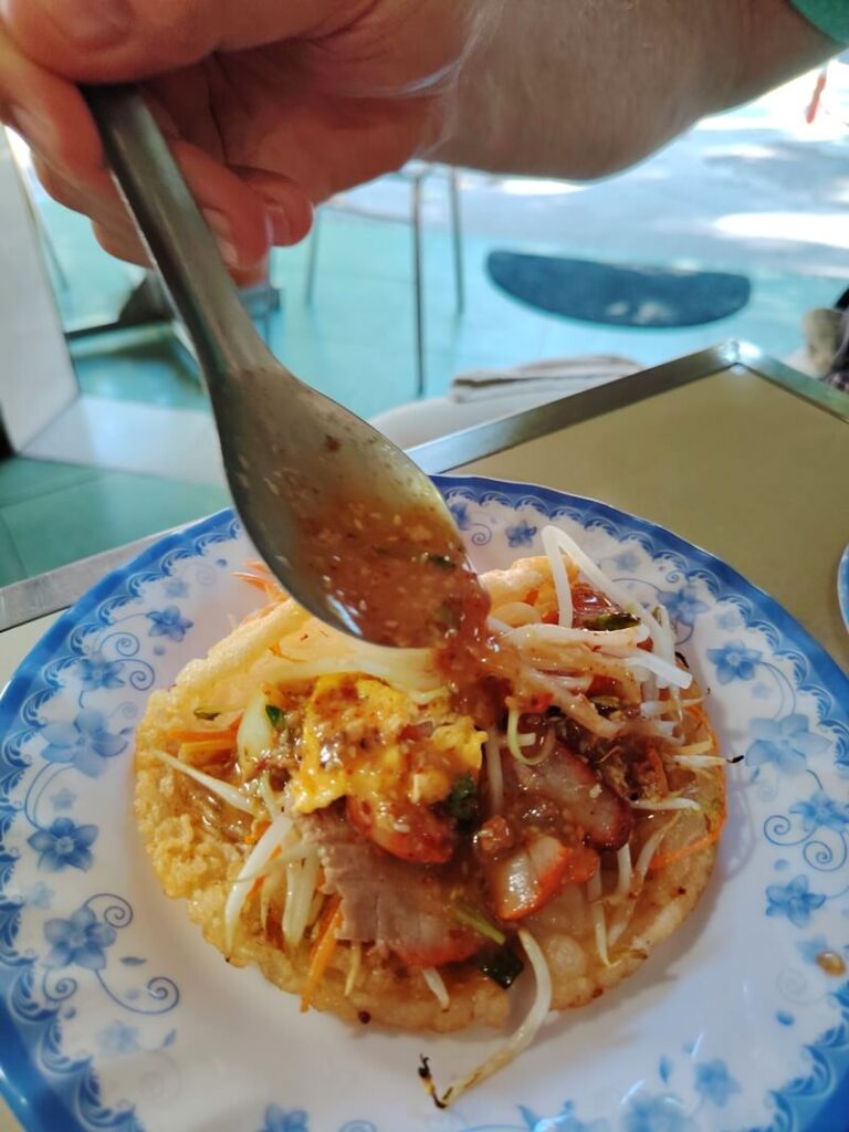 Close-up of Banh Khoai, a signature Hue dish, with sauce poured over the crispy pancake topping