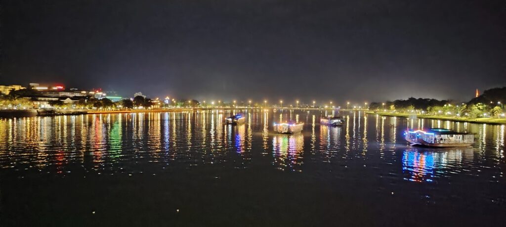 Panoramic view of the Perfume River at night with illuminated bridges and city lights.