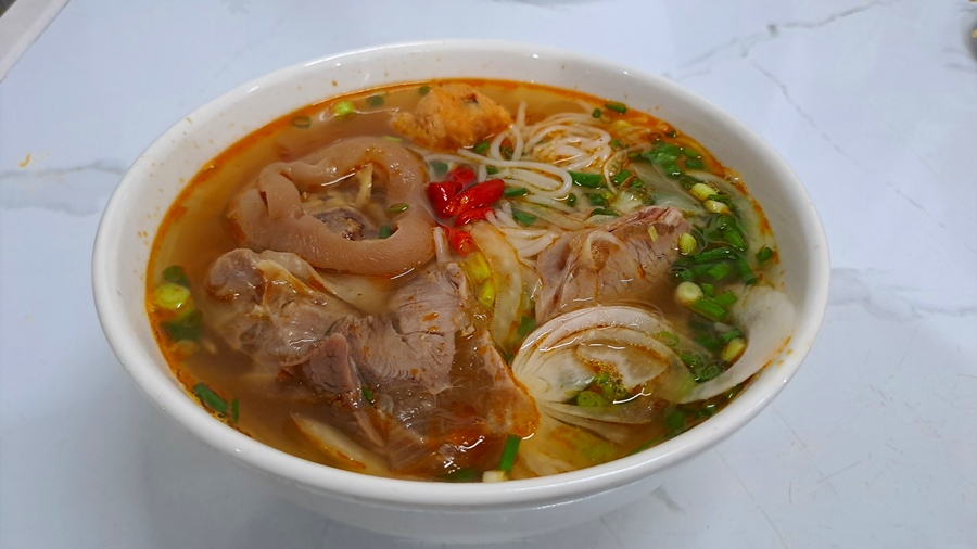 A bowl of traditional Bun Bo Hue served in a family-friendly restaurant in Hue, with vibrant colors and rich ingredients.