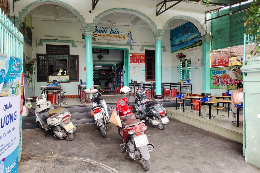 Front face of Huong Dumpling Restaurant with motorbike parking and tables already to serve traditional food