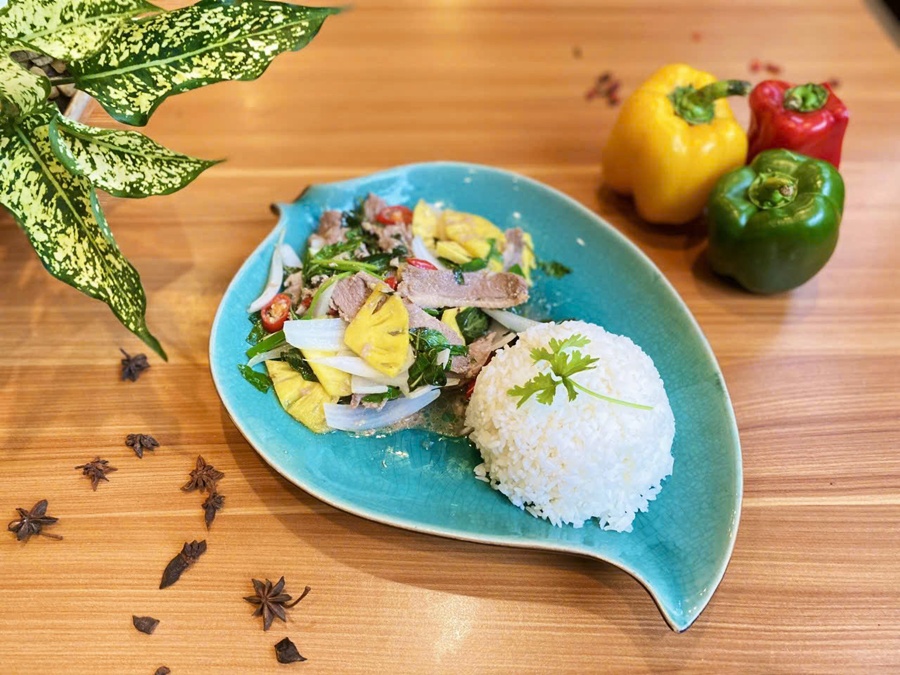 Vietnamese stir-fried pork with pineapple served with steamed rice on a green leaf-shaped plate at Spice Viet Hue restaurant