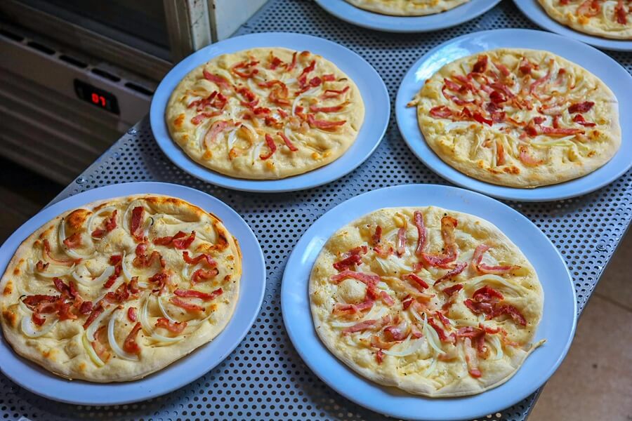 Four thin-crust Flammkuchen Pizzas (or similar flatbread) topped with bacon and onions, Western food option at DMZ Bar & Restaurant Hue.