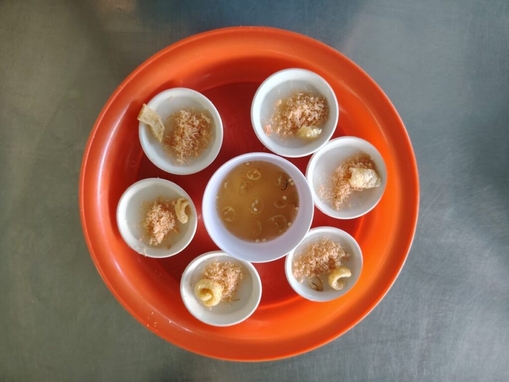 Banh beo Hue served in small bowls on a tray with shrimp, crispy pork skin, and fish sauce